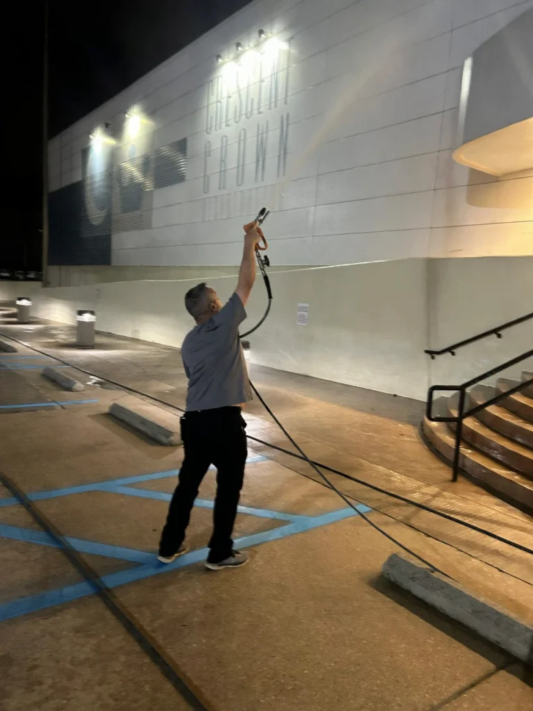 Hardy Power Washing crew member pressure washing the wall of a commercial building at night