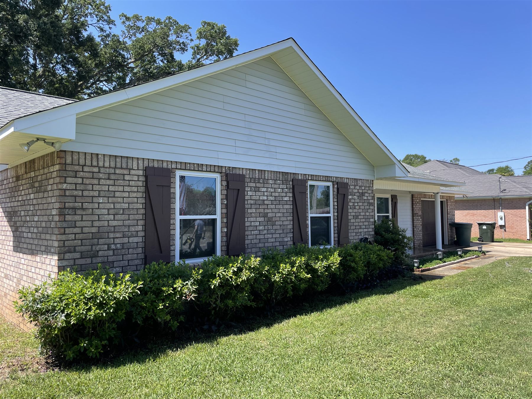 The same house after washing, with bright white siding and cleaner brick